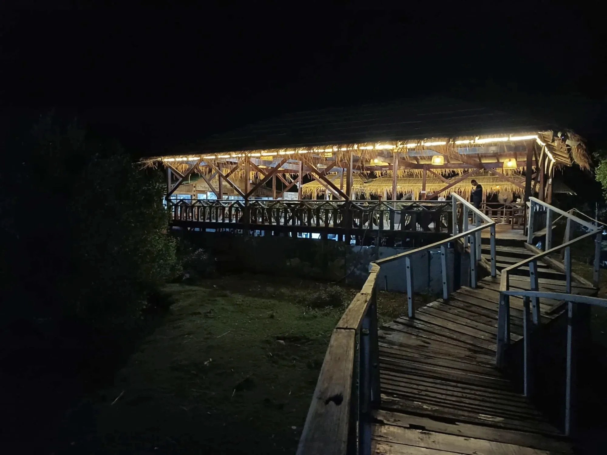 Sinbad Salmon Restaurant at night: an open-air thatched dining hall reached by a wooden boardwalk